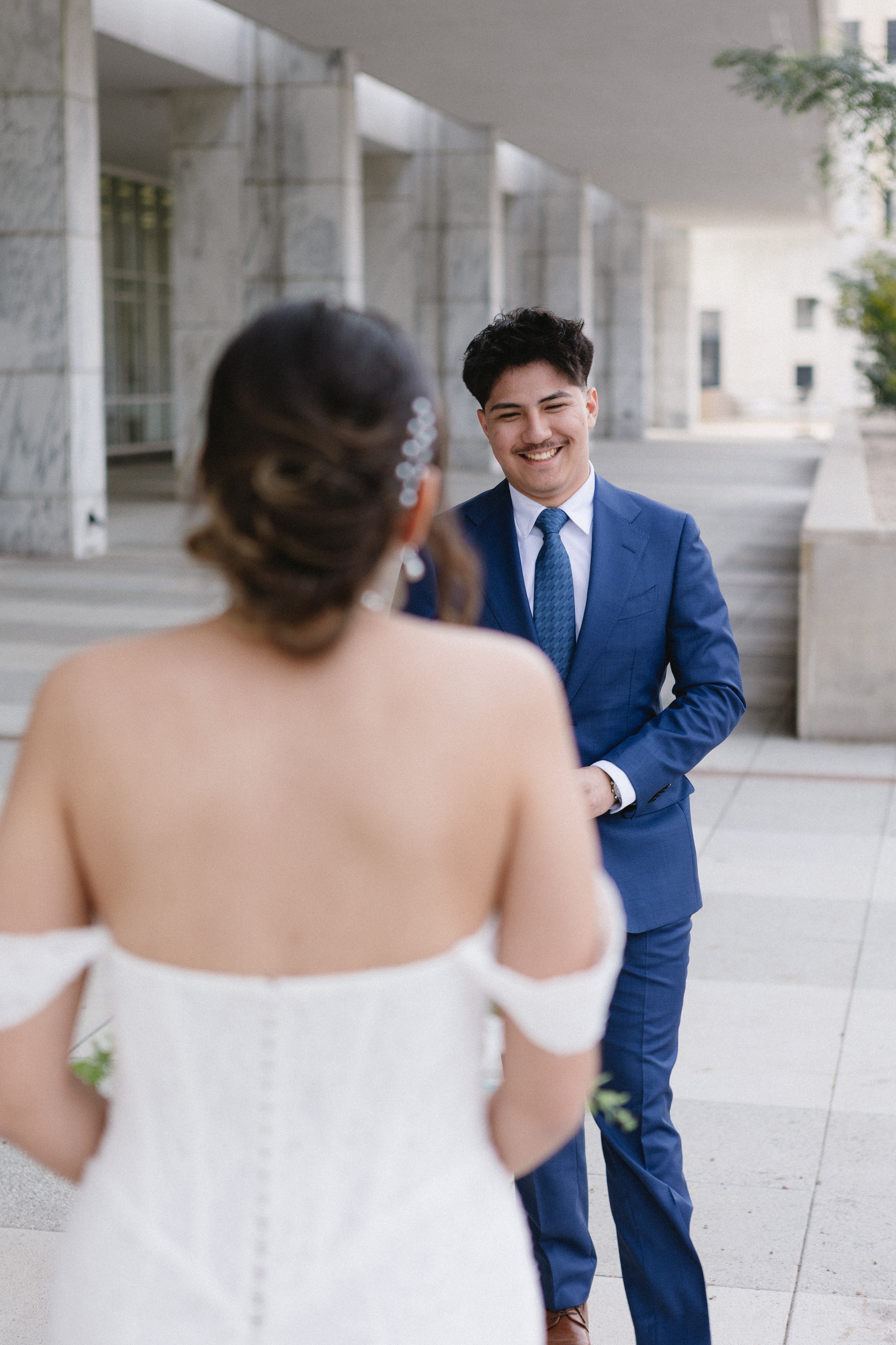A groom smiling as he sees his bride
