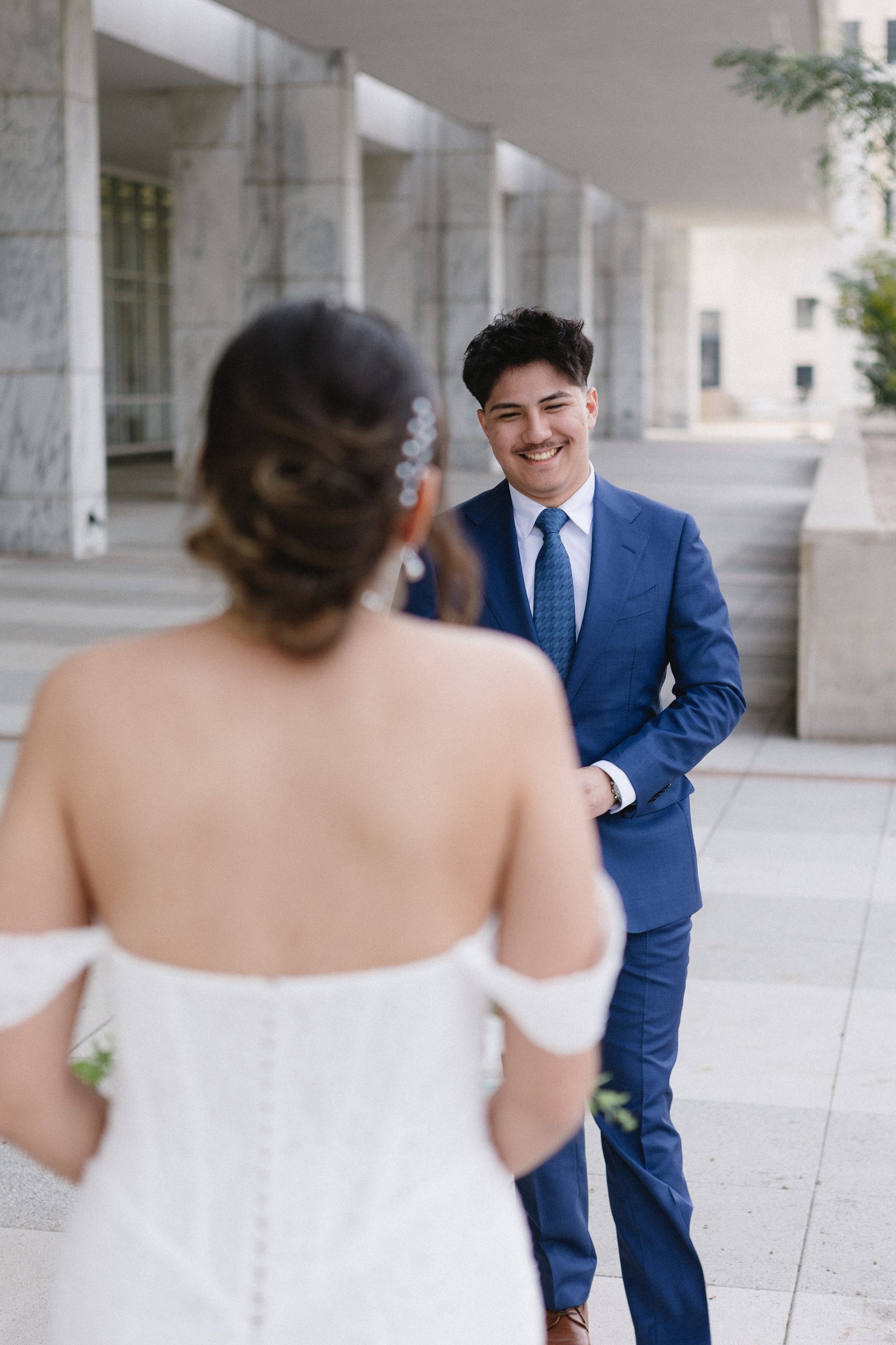 A groom smiling as he sees his bride